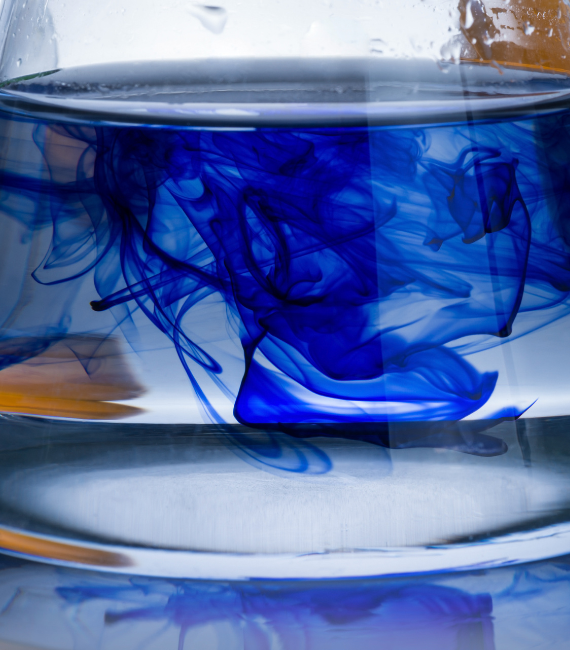 Close-up photo of a beaker filled with water and blue dye swirling in it