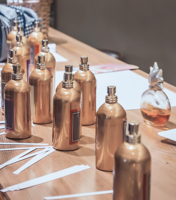 Several perfume bottles sitting on a wood table being reviewed 