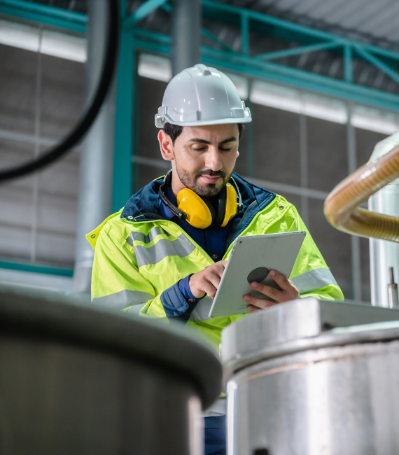 Man in high vis jacket and hard hat using tablet