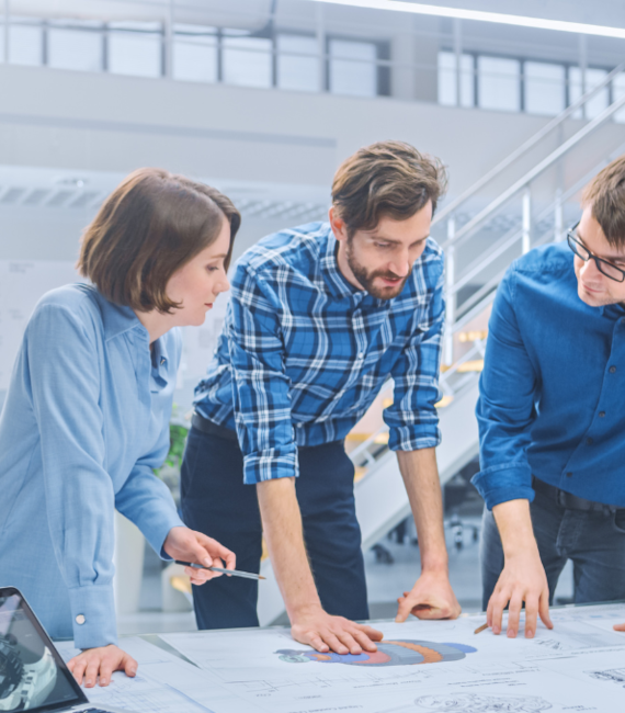 Group of employees standing around a table collaborating and planning