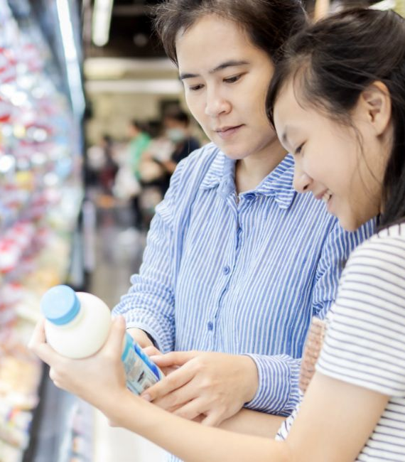 Two people in a grocery store handling a bottled beverage