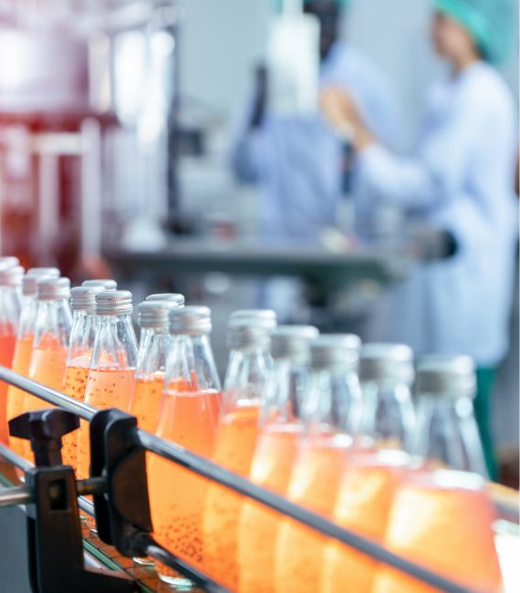 Selerant Devex PLM orange beverage bottles on a conveyor belt in manufacturing plant