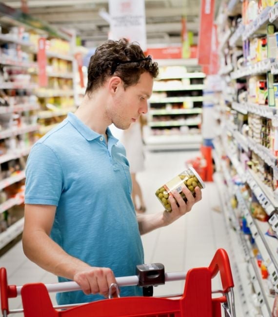 Selerant food and beverage compliance shopper checks label of product in supermarket